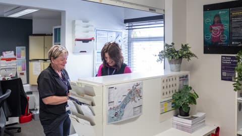 Sarah hall manager talking to her colleague Anette behind the hall reception desk
