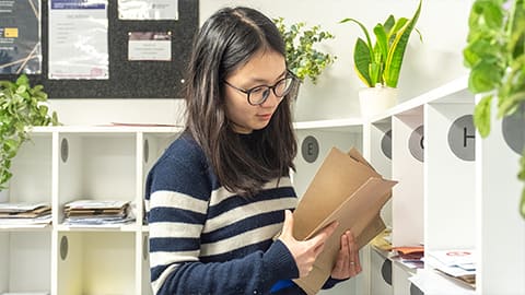 A student collecting their post at the post area of the Falkner Eggington student reception