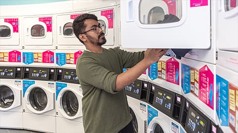 John Phillips student using the laundrette washing machines in the Hub central reception area