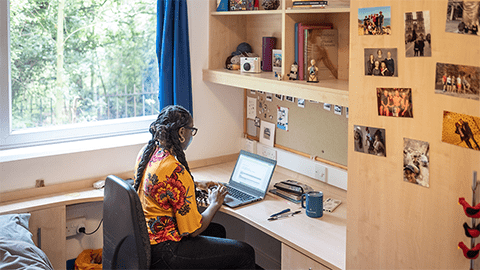 Student sat working at their spacious study desk at their room in John Phillips Loughborough student accommodation