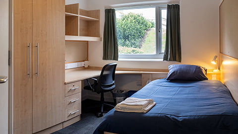 Modern and spacious bedroom in Robert Bakewell with a small double bed, large study desk and wardrobe and private en-suite bathroom