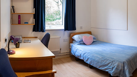 A standard bedroom with a study desk, bed and wash basin in Royce student accommodation at Loughborough University