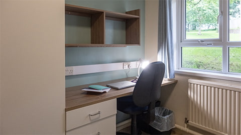 A study desk, shelves and chair in a standard Telford bedroom at Loughborough University student accommodation