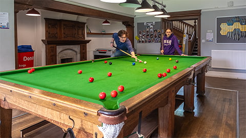 Students playing pool in the spacious common room in the gorgeous historic student accommodation The Holt