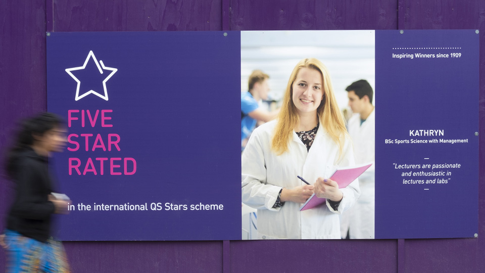 a woman walking past a hoarding