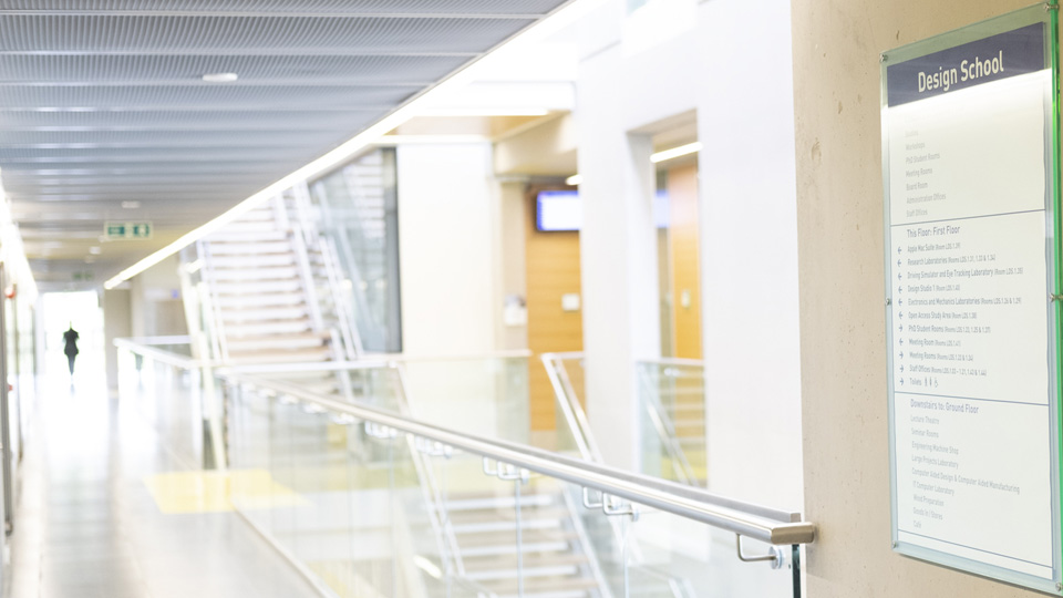 a Design School room list handing on a walkway wall