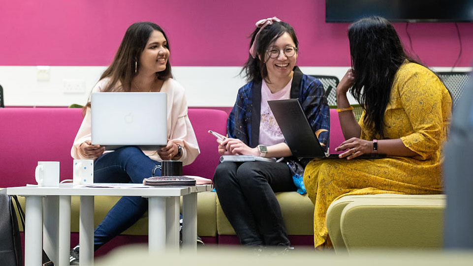 Three students chatting over laptops in Graduate House.