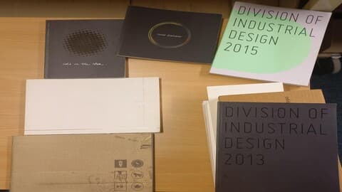 8 art degree show catalogues displayed on a table.