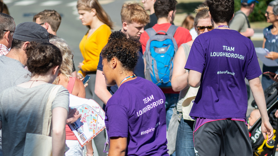 two Team Loughborough student helps with a crowd of visitors at an open day
