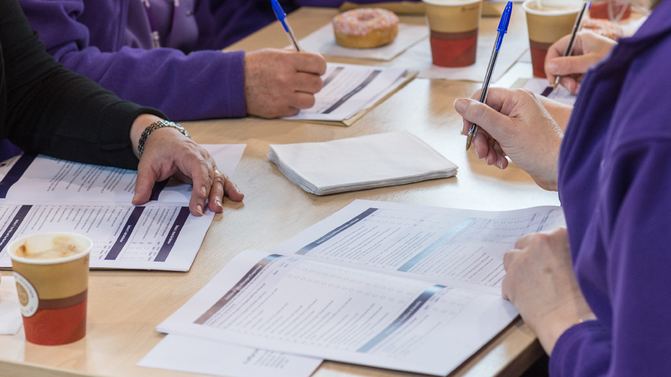 a group of women sitting at a desk filling in feedback forms