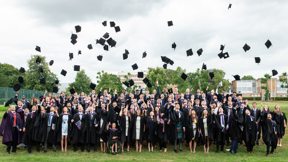 a group wearing graduation clothes throwing the hats up in the air