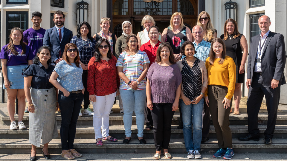 a group of people standing in front of the doors of the Hazlerigg building