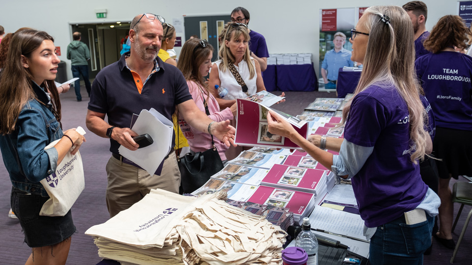people at an open day being given a prospectus and a bag