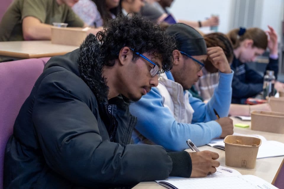Students sat in a row in a lecture theatre