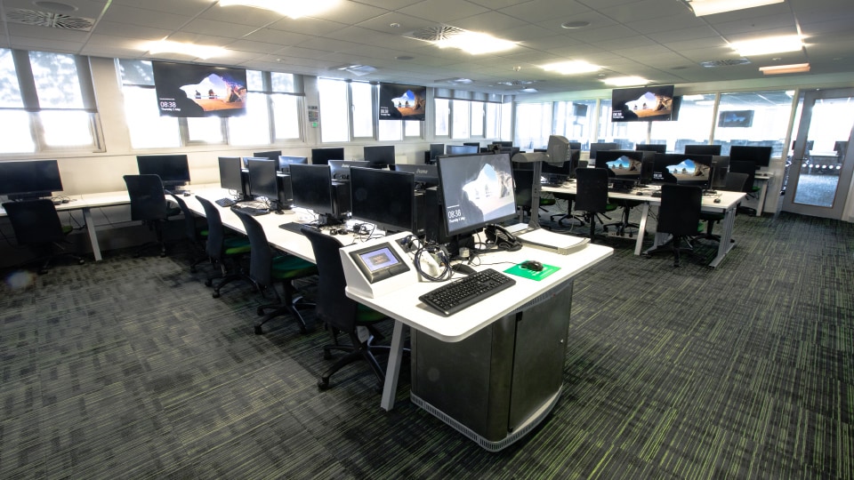 Haslegrave N004 - Modern teaching room with multiple computer stations, large screens, and natural light from windows.