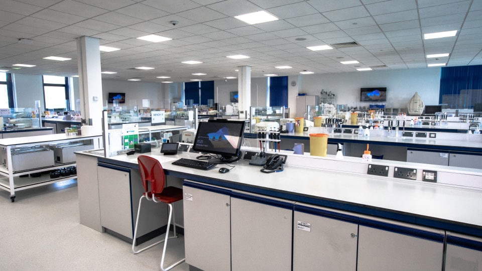 West Park Labs WPL203 - Spacious specialist lab with workstations, computers, lab equipment, and a red chair. Bright lighting and organized layout for teaching.