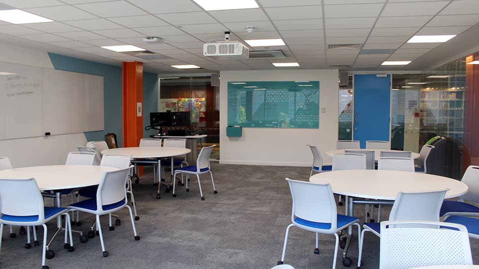 Medium-small space with round white tables, each with four white and blue chairs.
