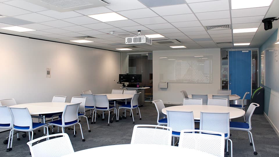 Medium-small space with round white tables, each with four white and blue chairs.