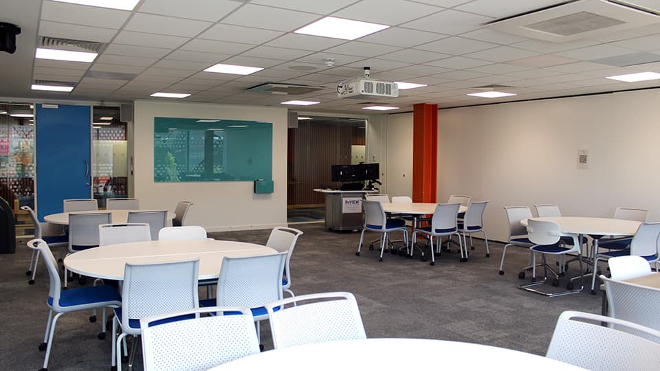 Medium-small space with round white tables, each with four white and blue chairs.