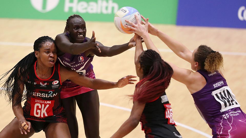 Four netball players on the court all trying to catch the ball