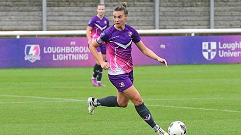 Kayleigh, in action, kicking a ball on a football pitch