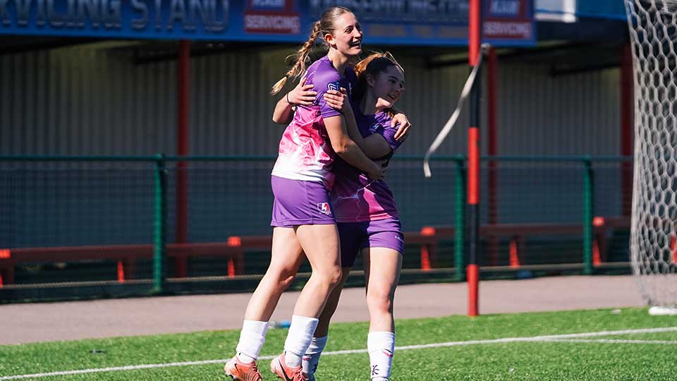 Two Lightning football players embracing on a football pitch