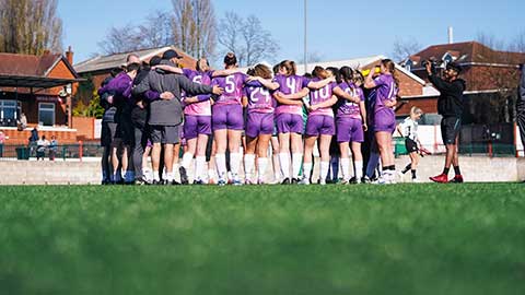 Lightning players stood together in a huddle on a football pitch