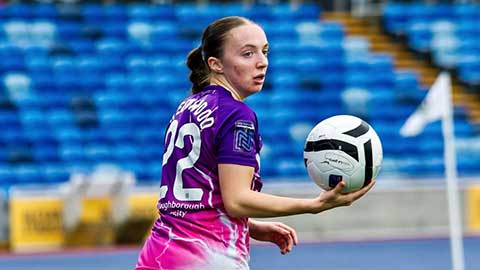 Player Doris Greenwood holding a football with her back turned to the camera