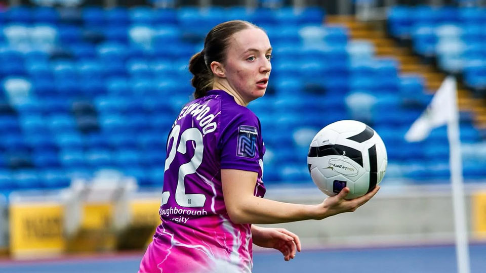 Player Doris Greenwood holding a football with her back turned to the camera