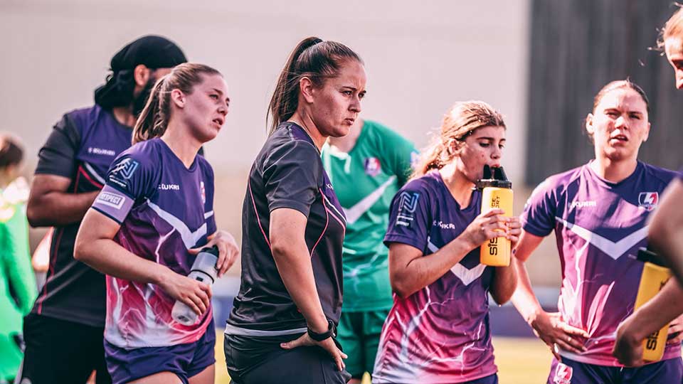 Sarah Richardson standing on a football pitch with Loughborough Lightning football players