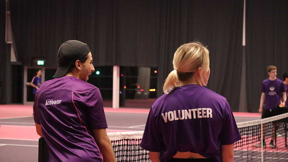 Two students with their back to to the camera's wearing t-shirts that read 'activator' and 'volunteer'
