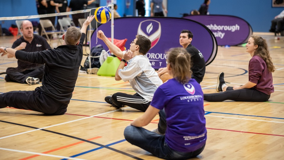A group of people are playing sit down volleyball.