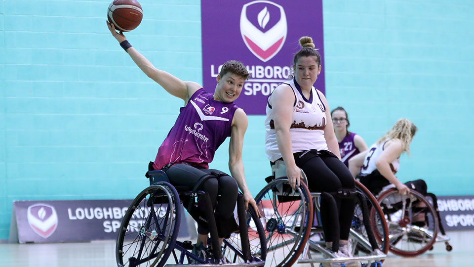 Wheelchair basketball players during a match with one holding the ball in the air