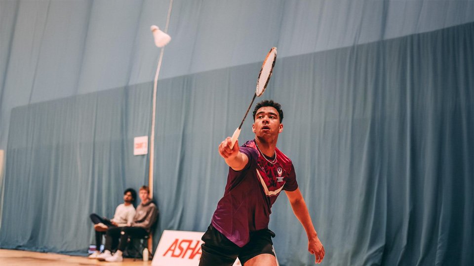 A photograph of a Loughborough mens badminton player hitting the shuttlecock