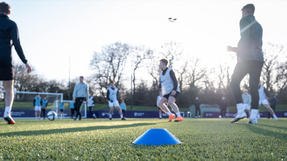 A low-to-the-ground photograph of a men's football squad doing training drills
