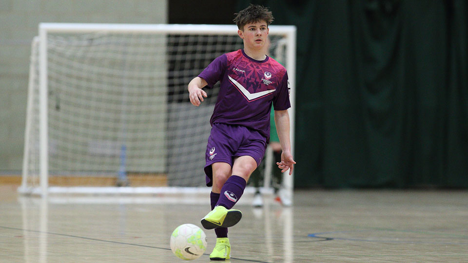 A futsal player in Loughborough kit about to kick the ball. The home goal is in the background