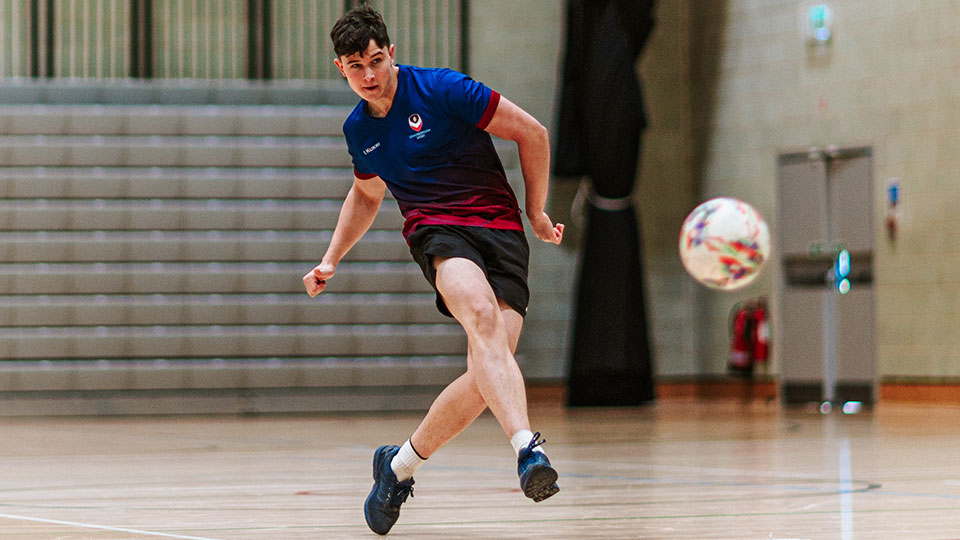 A futsal payer preparing to kick the ball that is in the air