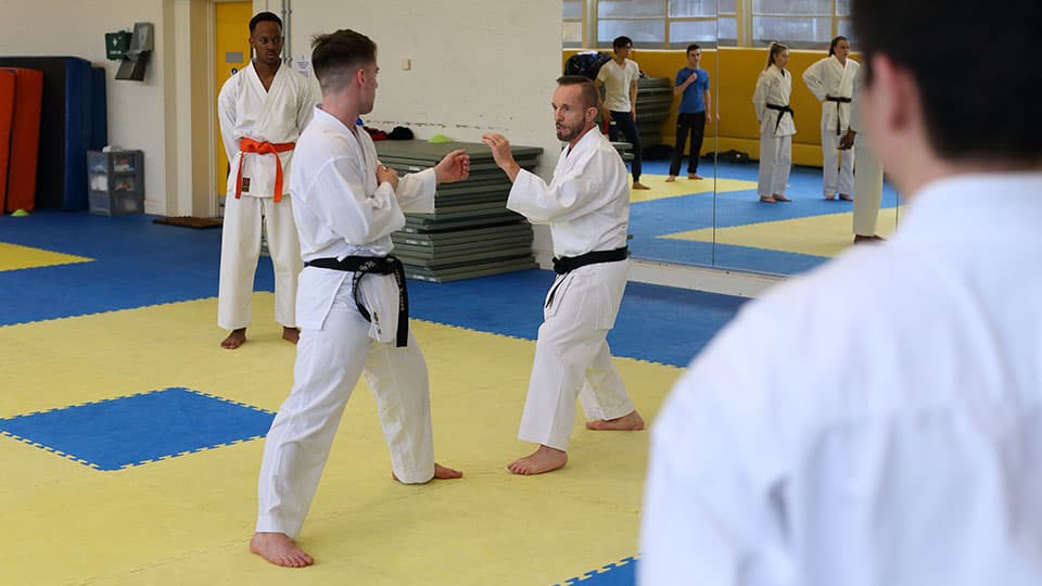 Judo participants watching a two person demonstration