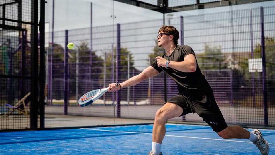 A padel player about to hit the ball with their racket