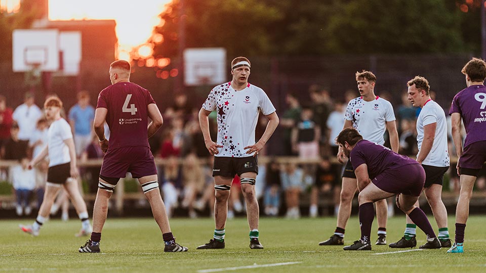 A men's rugby union hall sport match in progress with the sun setting in the background
