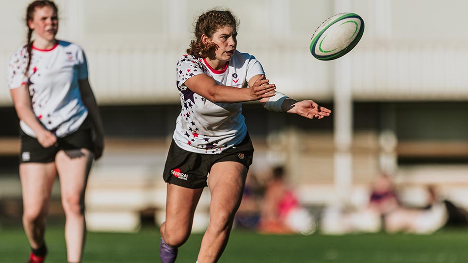 Two players on the rugby pitch and one is about to catch the ball