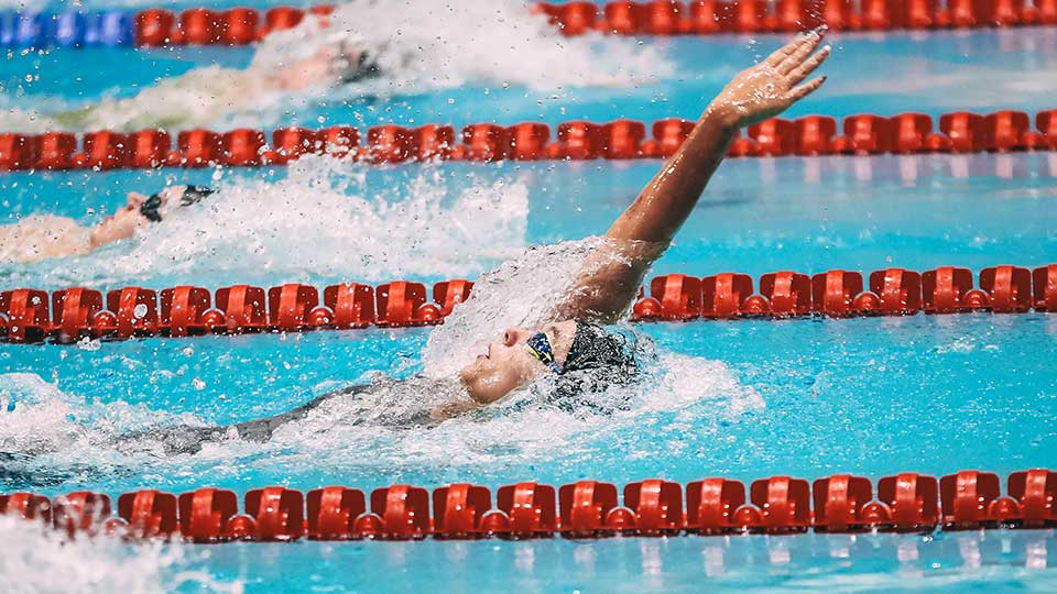 A female swimmer about to get out of the pool