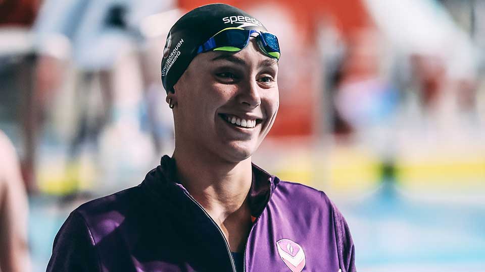 A swimming relay with swimmers in the pool and swimmers about to jump in.
