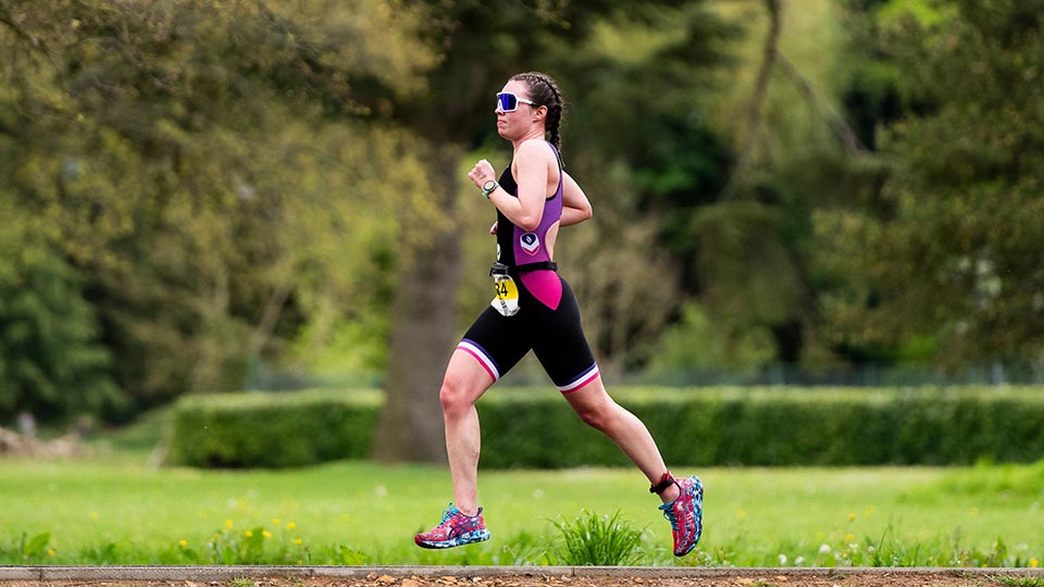 A triathlete running outdoors with trees in the background