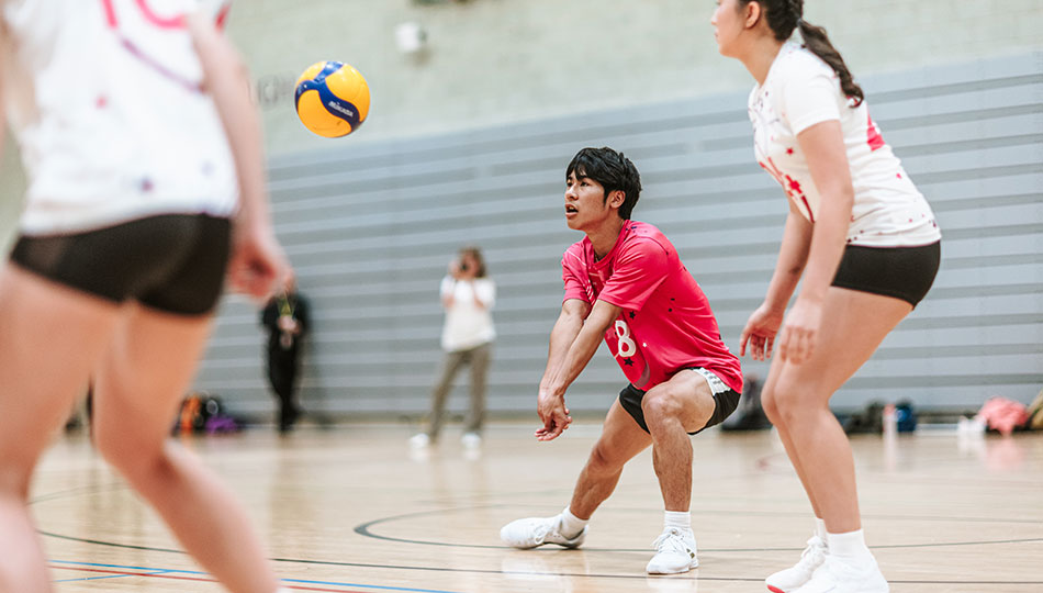 A student volleyball match in progress with one player about to hit the ball