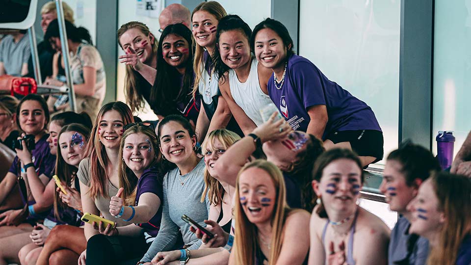 A group of spectators smiling at the side of the pool