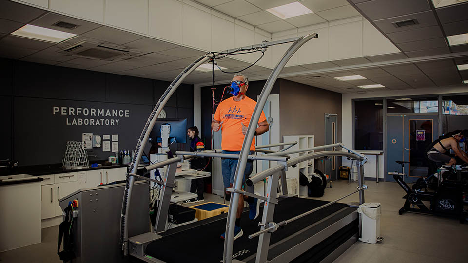 A triathlete is running on the lab treadmill wearing a mask.