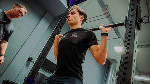 A triathlete is working with an strength and conditioning practitioner in the gym.