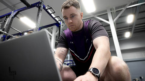 An S&C coach is pulling a report together in the gym.