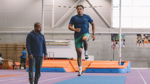 a man jumping and a coach watching
